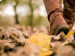 Woman walking on street full of dead leaves during Autumn